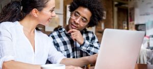 Two people talking in front of a laptop, representing the decision-making process for hiring a nonprofit strategic planning consultant.